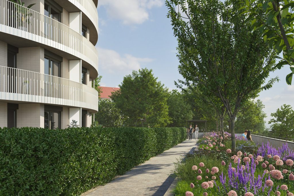 Promenáda se záhony fialových a růžových květin podél zaoblené fasády domu s balkony