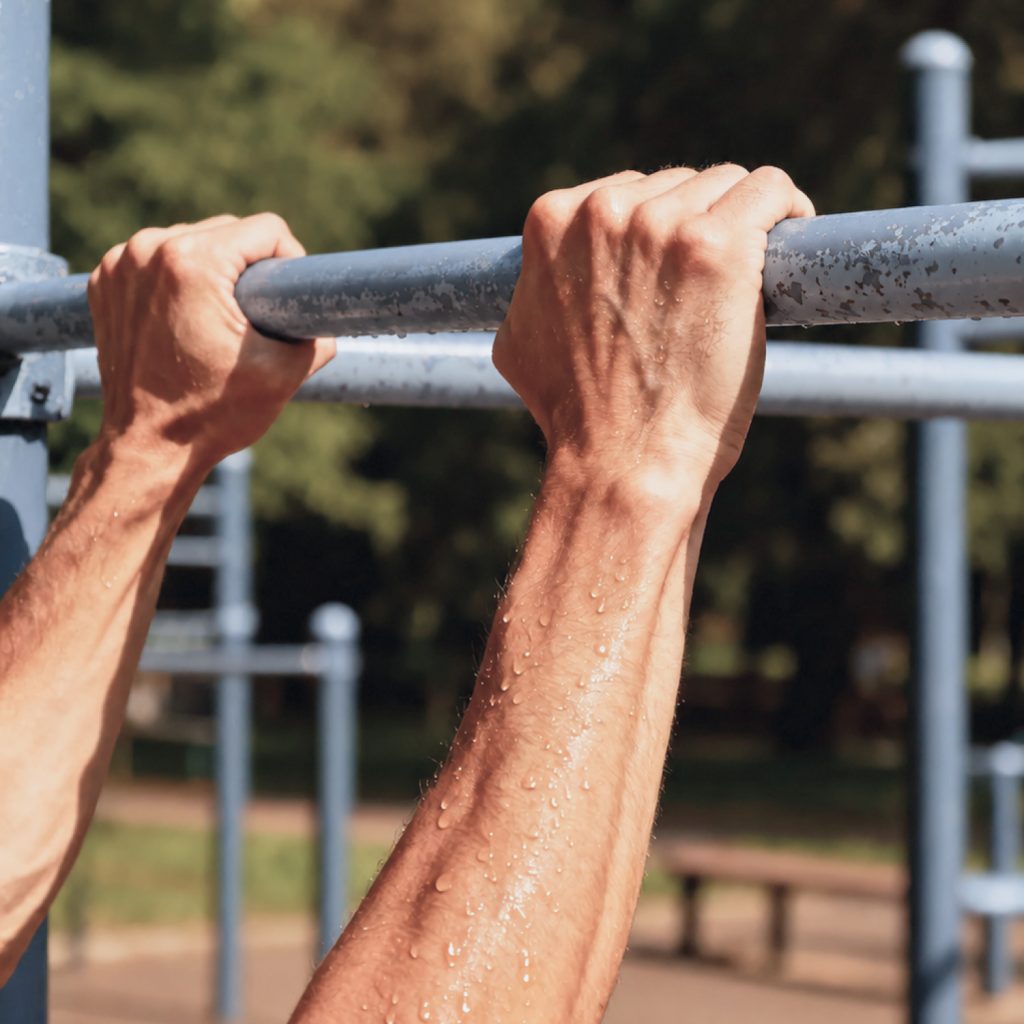 Ruce na hrazdě venkovního workoutového hřiště